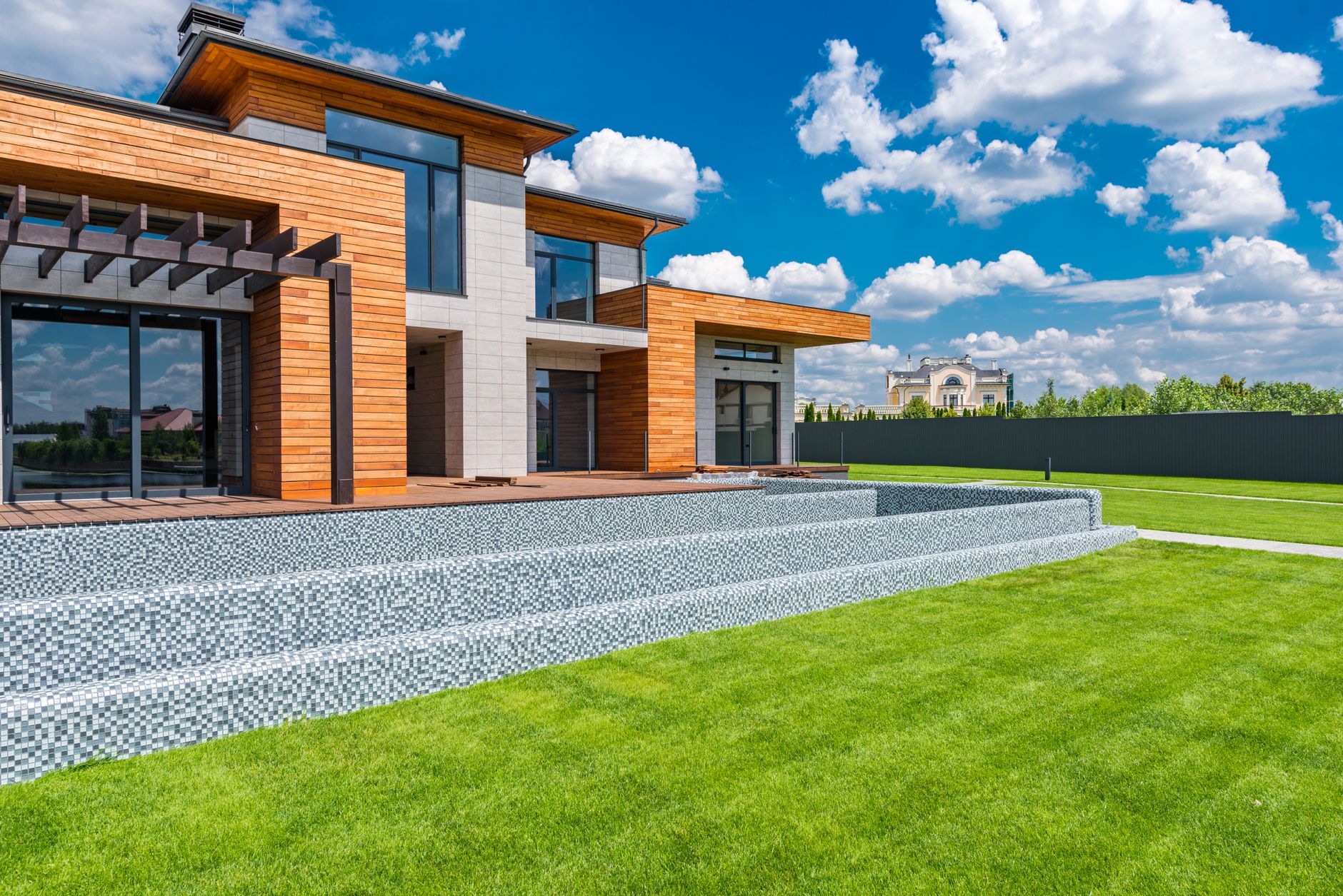 Elegant luxury country home with sprawling gardens and stone facade under a clear sky.